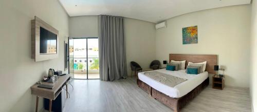 ein Schlafzimmer mit Bett, Schreibtisch und Fenster in der Unterkunft Eventi Club by cité des sports adarissa in Fès