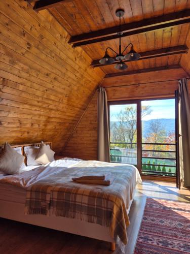 a bedroom with a bed and a large window at Twin Cabins / Cabanele Gemene in Suceava