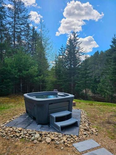 a hot tub in the middle of a field at Spa & River - Hidden chalet - Chalet cache in Saint-Alexis-des-Monts