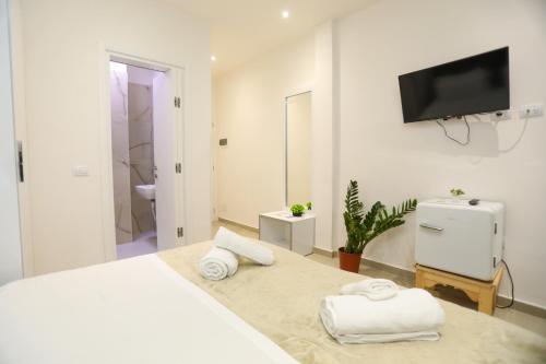 a white bedroom with a bed and a tv on the wall at Hotel SUNSET GL in Vlorë