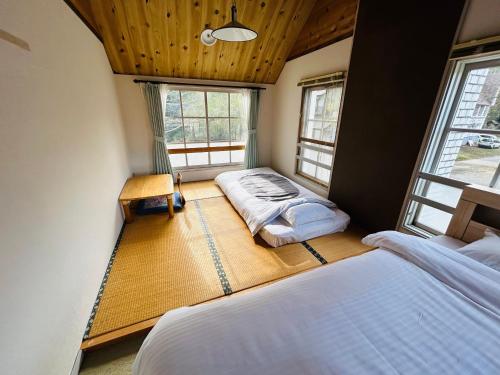 a bedroom with two beds and two windows at Hakuba Snow Fox in Hakuba
