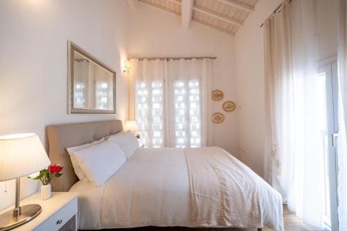 a white bedroom with a bed and a window at Il fienile del borgo in Prato