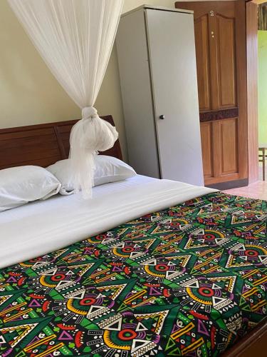 a bed with a colorful blanket on top of it at Cross Roads BackPackers Entebbe in Entebbe