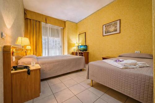 a hotel room with two beds and a window at Hotel Remin Plaza in Rimini