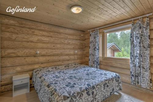 a bedroom with a bed in a log cabin at Holiday Home Tattimetsä in Sysmä