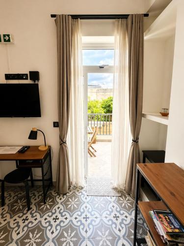 a room with a desk and a door with a window at Iris -Paola Modern Townhouse in Paola