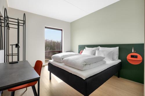 a bedroom with a bed with a green headboard and a table at Comfort Hotel Grenlandsporten in Langangen