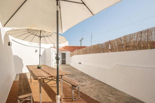 a patio with a wooden table and an umbrella at GuestReady - Enchanting retreat in Alcácer do Sal in Alcácer do Sal