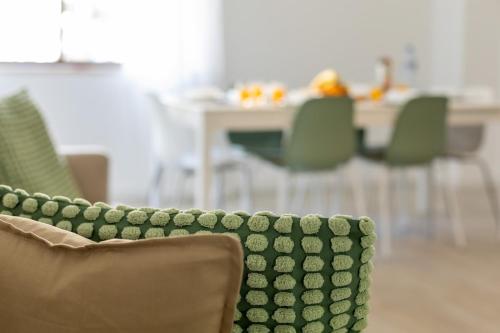 a green couch sitting in a room with chairs at 3BR Comfort & Convenience apt in central Massamá in Queluz