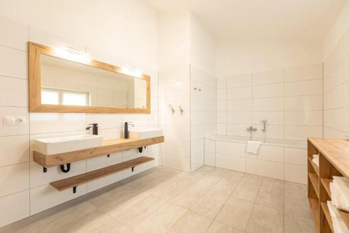 a bathroom with a sink and a mirror and a tub at Luxalps- BergZeit- Inzell- Sommerpool- Sauna- Wandern- Chiemgau Card in Inzell