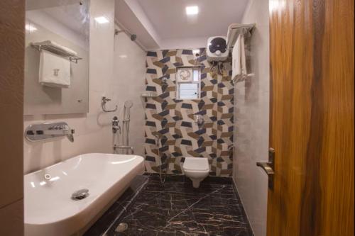 a bathroom with a white sink and a toilet at Hotel Orion Crystal in Kolkata