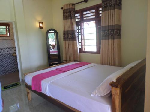 a bedroom with a large white bed with a window at Kirinda Beach Front Hotel in Kirinda
