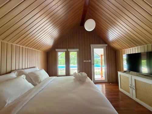 a bedroom with a large white bed and a flat screen tv at Ther lay beach resort in Sikao