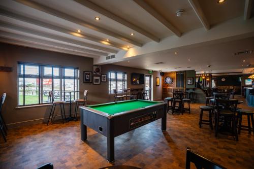 a pool table in a room with tables and chairs at The Aviator, formerly Smugglers Cove, Clacton On Sea by Marston's Inns in Clacton-on-Sea