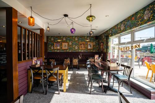 a dining room with tables and chairs and a window at The Aviator, formerly Smugglers Cove, Clacton On Sea by Marston's Inns in Clacton-on-Sea