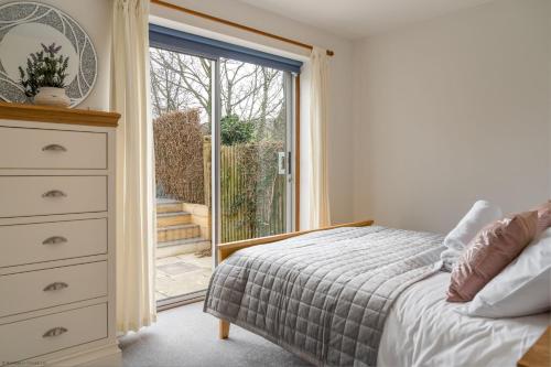 a bedroom with a bed and a dresser and a window at Kernow House in Croyde
