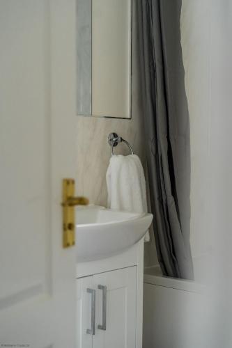 a bathroom with a white sink and a mirror at Kernow House in Croyde
