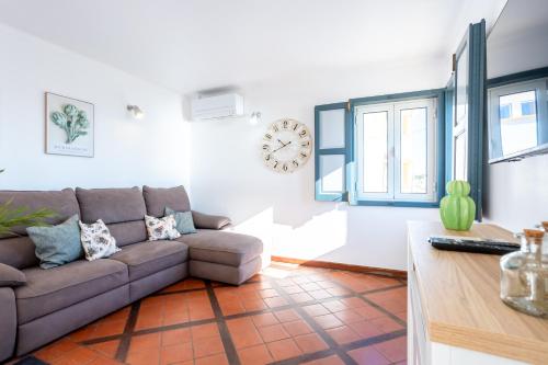 a living room with a couch and a clock on the wall at Casas do Zé Zambujeira do Mar in Zambujeira do Mar