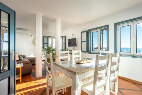 a dining room and living room with a table and chairs at Casas do Zé Zambujeira do Mar in Zambujeira do Mar