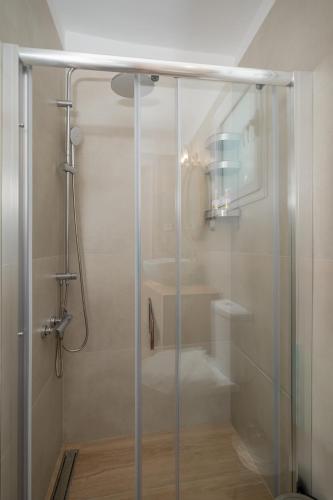 a shower with a glass door in a bathroom at Elida Inn Near ATH Airport in Markopoulo