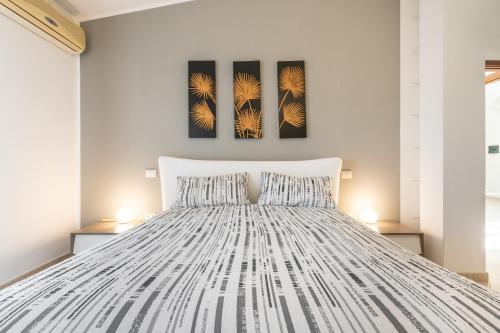 a bedroom with a white bed with two paintings on the wall at Casa Dudú in Quartucciu