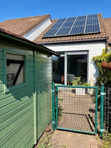 a green shed with a gate with solar panels on it at House & garden l'Hippodrome in Bredene