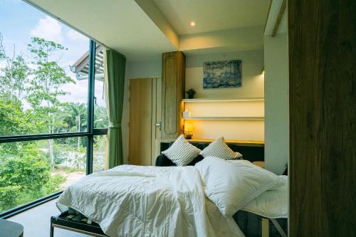 a bedroom with a bed and a large window at Tabebuia House ทาเบบูย่าเฮ้าส์ in Pathiu