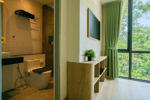 a bathroom with a toilet and a window at Tabebuia House ทาเบบูย่าเฮ้าส์ in Pathiu
