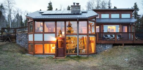 a large glass house with a roof on a hill at Fairplay Coyote Cabin in Fairplay