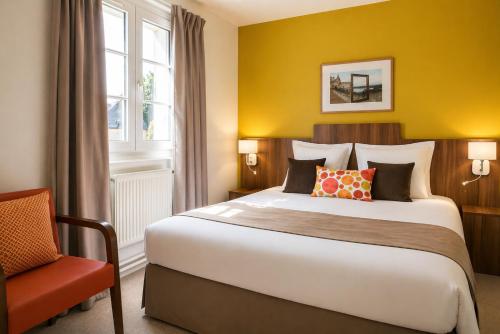 ein Hotelzimmer mit einem großen Bett und einem Stuhl in der Unterkunft Logis Hôtel Chaptal, Amboise in Amboise