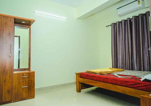 a bedroom with a bed and a dresser and a mirror at Ocean Breeze Service Apartment in Malpe