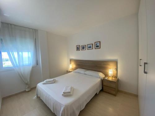 a bedroom with a large white bed and a window at Apartament Sara in L'Eucaliptus