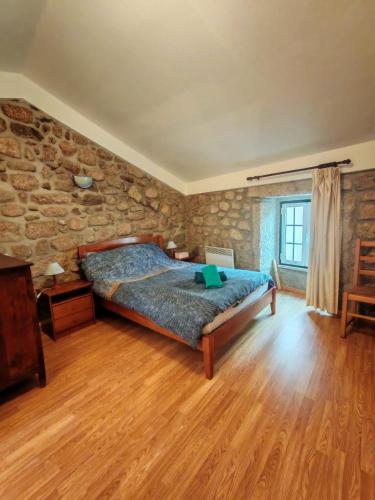 a bedroom with a bed and a stone wall at Stone House - Waterfalls, Nature Stay in Louriçal do Campo