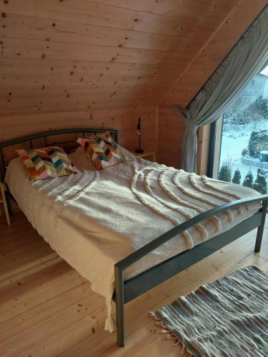a bed in a wooden room with a window at Domki Dobrogoszcz in Dobrogoszcz