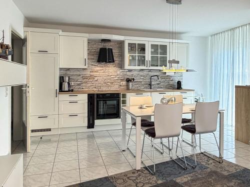 a kitchen with white cabinets and a table and chairs at Windwatt 2 in Zingst