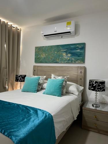 a bedroom with a bed with blue and white pillows at Apartamento COMPLETO Nuevo Norte de Valledupar-1 Habitación, Balcón y Parqueadero in Valledupar