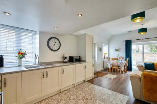 a kitchen and living room with a clock on the wall at Host & Stay - Beagle Barn in Withington