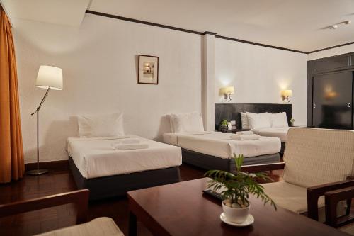 a hotel room with two beds and a table at Le Charme Vientiane Hotel in Vientiane