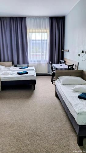 a bedroom with two beds and a table and chairs at Hostel Helios in Września