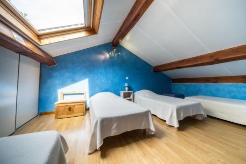 a room with two beds and a blue wall at Gite Fontaine in Le Soulié