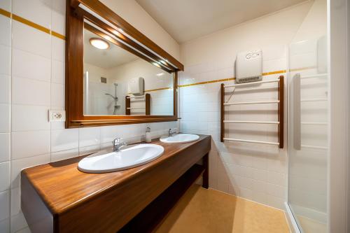 a bathroom with two sinks and a mirror at Gîte Des Myrtilles in Le Soulié