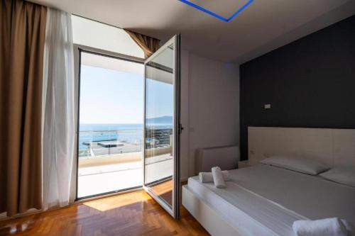 a bedroom with a bed and a large glass window at Hotel Lusini in Vlorë