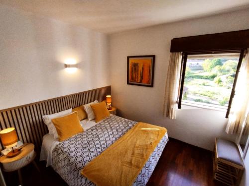 a bedroom with a bed with yellow pillows and a window at Casa Hóspedes Polido in Termas de Sao Pedro do Sul