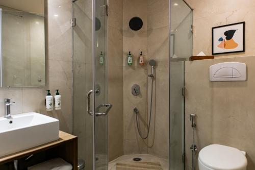 a bathroom with a shower and a toilet and a sink at Udman Hotel Panchshila Park in New Delhi