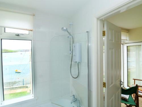 a white bathroom with a shower and a window at 24 The Salcombe in Salcombe