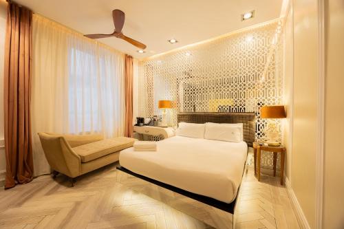 a bedroom with a bed and a couch and a chair at Abalú Collection Hotel Boutique Gran Via in Madrid
