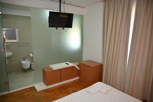 a bathroom with a bed and a shower and a television at Hotel Lusini in Vlorë