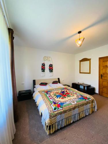 a bedroom with a bed with a colorful blanket on it at Pensiunea Casa Mariuca in Văleni