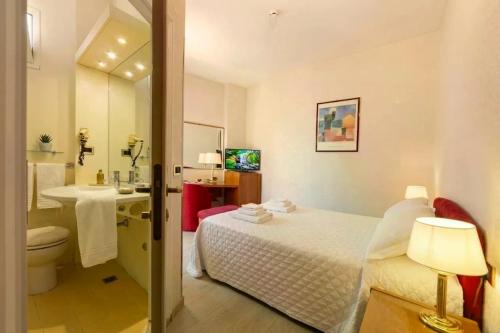 a bathroom with a bed and a toilet and a sink at Hotel Kursaal in Rimini