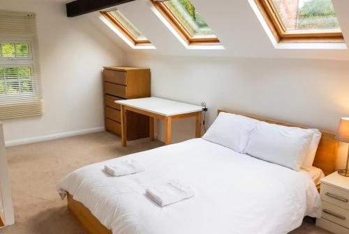 a bedroom with a bed and a desk and windows at Character Cottage with Private Parking in Central Leeds, Near LGI in Leeds